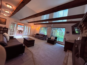 A spacious living room with a fireplace, large windows, and a cozy seating area.