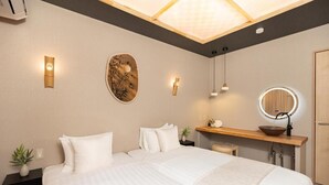 Une chambre d’hôtel moderne dotée d’un grand lit, de tables de chevet, d’une coiffeuse avec un miroir et d’un luminaire au plafond.