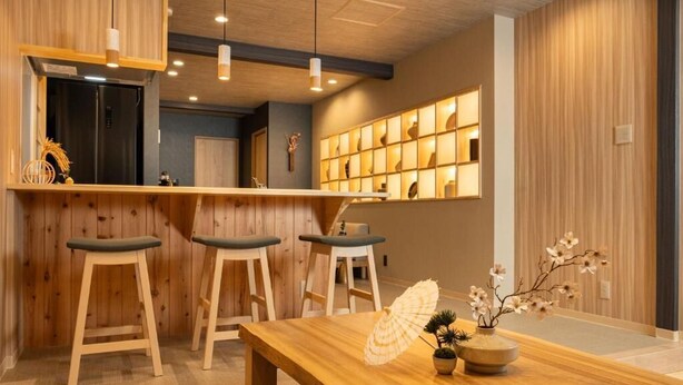Un coin bar en bois avec des tabourets, une table en bois et un vase rempli de fleurs.