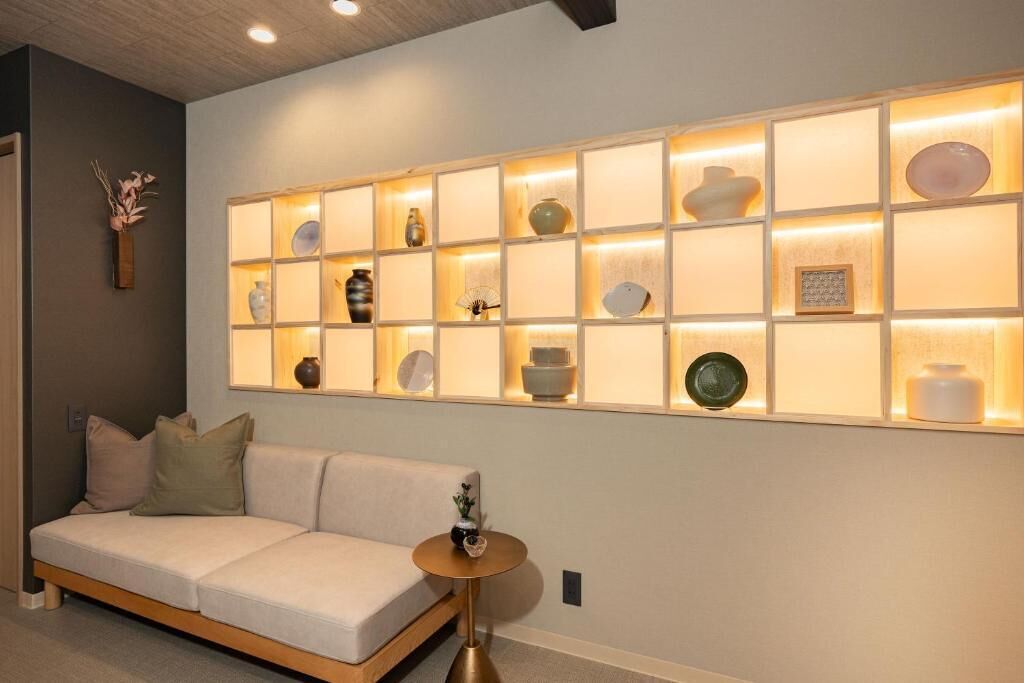 A modern interior with a sofa, a wall-mounted shelf with decorative items, and a round table.