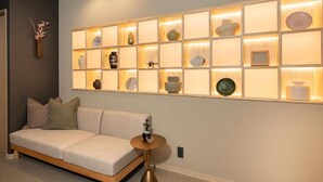 Un intérieur moderne avec un canapé, une étagère murale agrémentée d’objets décoratifs et une table ronde.
