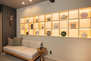 A modern interior with a sofa, a wall-mounted shelf with decorative items, and a round table. - JAPAVISTA Yumeno (BAIKA, KONOHANA WARD)