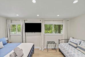Une chambre avec deux lits, une télévision et une fenêtre avec des rideaux.