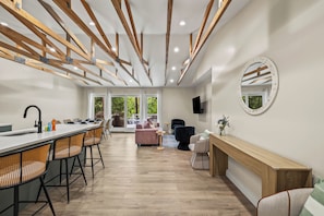 Une cuisine moderne avec un coin bar, des poutres en bois et une grande fenêtre.