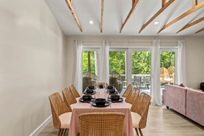 Ein Essbereich mit einem Tisch, gedeckt für sechs Personen, umgeben von Korbstühlen und Blick auf Grünflächen.