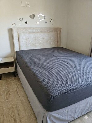 Un dormitorio con cama, mesita de noche y pared decorada con adornos en forma de corazón.