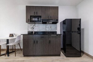 Eine moderne Küche mit dunklen Holzschränken, einer schwarzen Mikrowelle, einem Einbauofen, einem schwarzen Kühlschrank und einer Marmor-Spritzschutzwand.