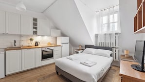 A modern room with a kitchen, a bed, and a TV.