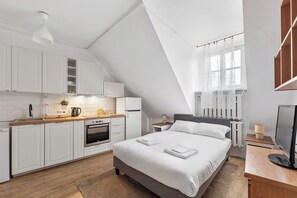 A modern room with a kitchen, a bed, and a TV.
