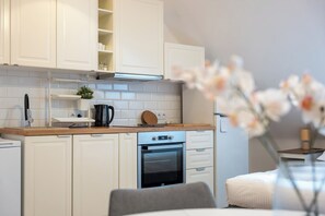 A modern kitchen with white cabinets, a built-in oven, and a wooden countertop.