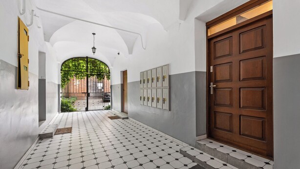 A hallway with a tiled floor, a wooden door, and a set of lockers.