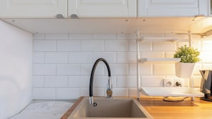 A kitchen with white cabinets, a sink with a modern faucet, and a wooden countertop.