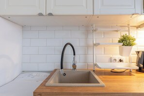 A kitchen with white cabinets, a sink with a modern faucet, and a wooden countertop.