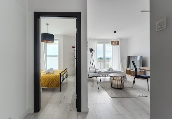 Une chambre d’hôtel moderne équipée d’un lit, d’un bureau, d’une chaise, d’une télévision et d’un balcon avec vue.