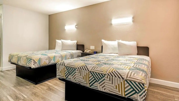 Une chambre double avec deux lits, une table de chevet et un luminaire fixé au mur.