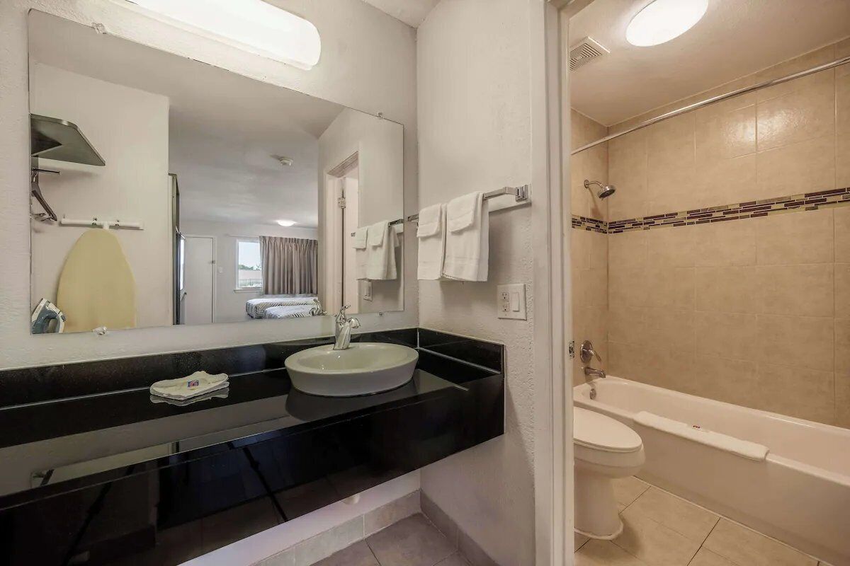 A bathroom with a round sink, a mirror, a bathtub, and a shower.