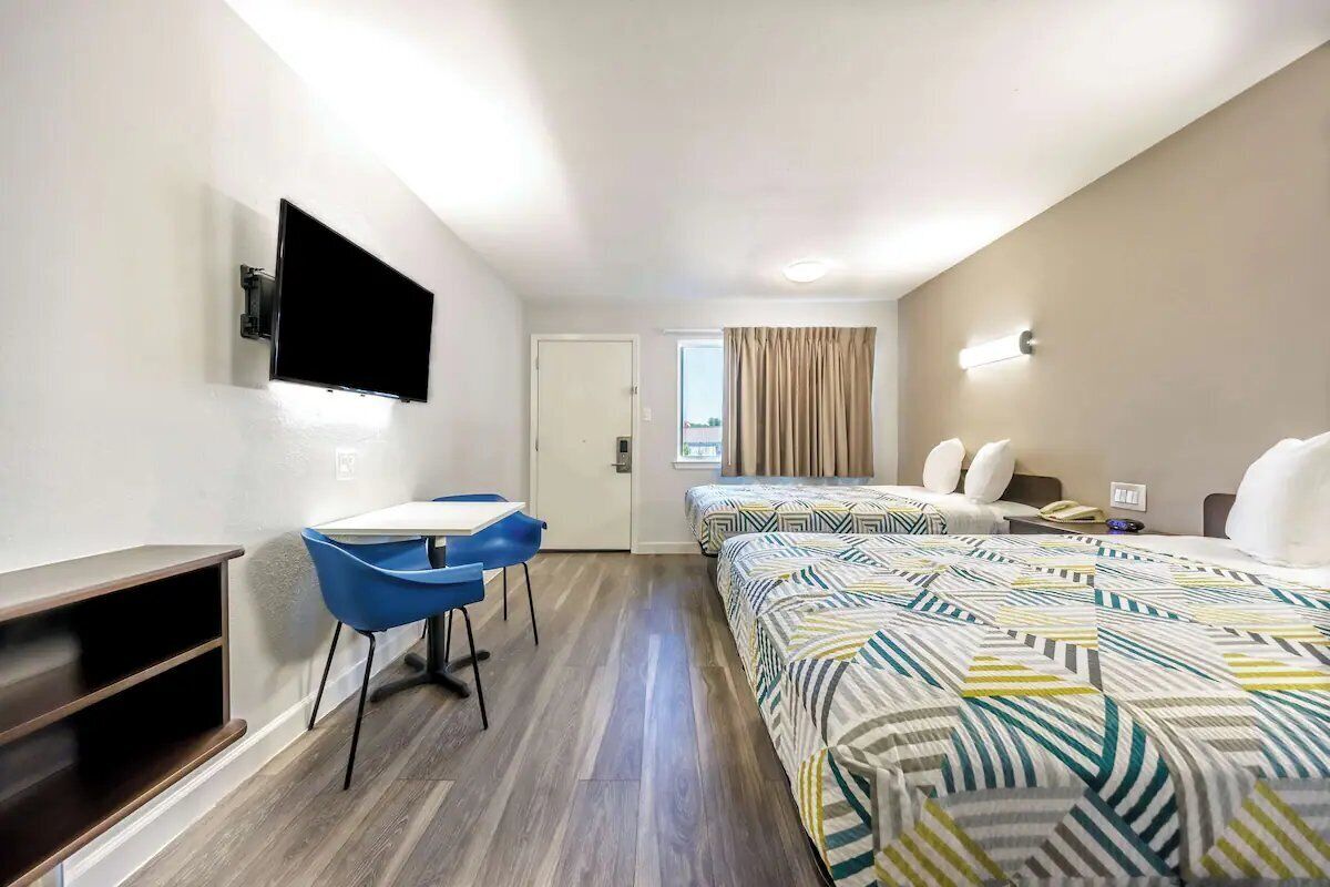 A hotel room with a bed, a desk, a chair, a TV, and a window.