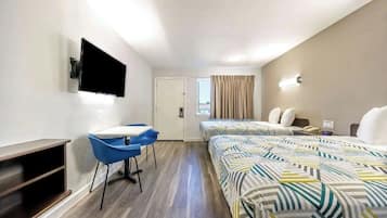 A hotel room with a bed, a desk, a chair, a TV, and a window.