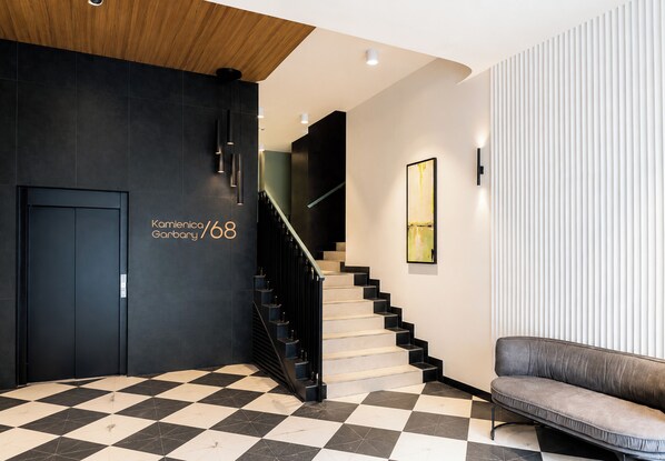 A modern lobby with a checkered floor, a staircase, a sofa, and a wall-mounted artwork. - Garbary Old Town Chic Studio (Poznań)