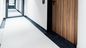 Ein Flur mit einer Holztür, einem Rauchmelder und einem Schild, das Zimmer Nummer 52 anzeigt.
