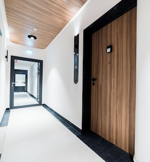 A hallway with a wooden door, a fire alarm, and a sign indicating room number 52. - Garbary Old Town Chic Studio (Pozna ń)