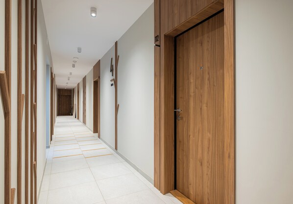 A hallway with wooden doors and a tiled floor. - Heweliusza 8 Harmony Apartment (Warszawa)