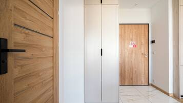 Un corridoio con una porta in legno, una porta bianca con un cartello e un pavimento in marmo.