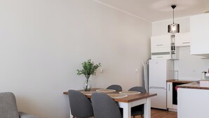A modern kitchen with white cabinets, a wooden countertop, and a dining area with a table and chairs. - Długa Homely Apartment (Toruń)