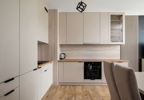 Una cucina moderna con mobili bianchi, un piano di lavoro in legno e un forno integrato.