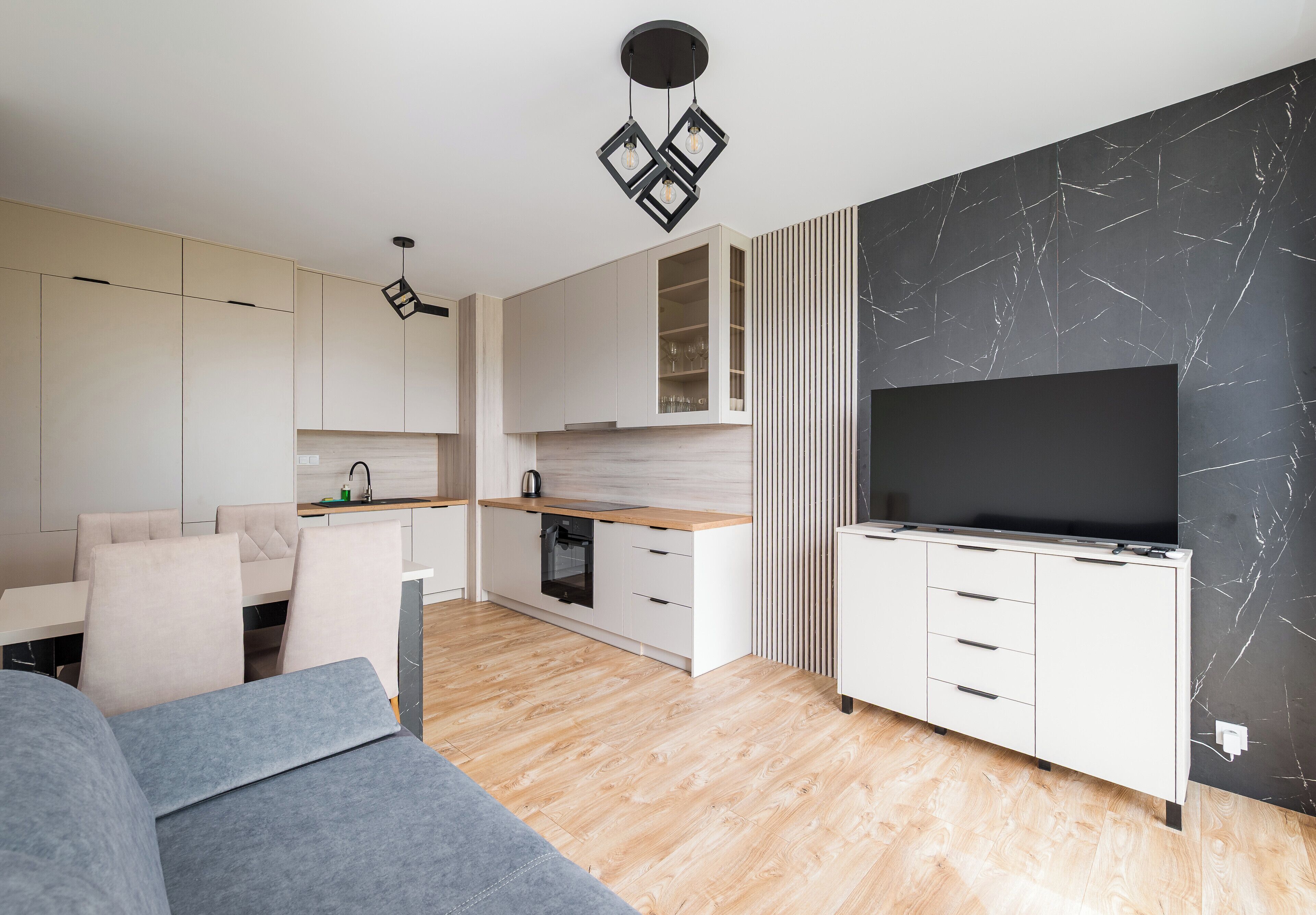Una cocina moderna con armarios blancos, encimera de madera y televisión empotrada.