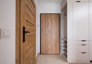 Ein Korridor mit einer Holztür, einem weißen Kleiderschrank und einem weißen Schrank.