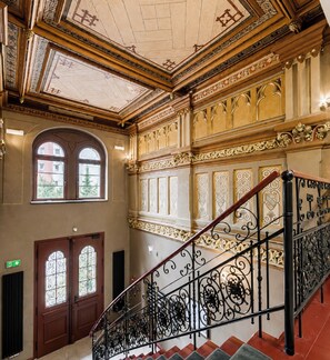 Eine prächtige Treppe mit aufwendigen Metallgeländern und einer Decke mit filigranen Verzierungen.