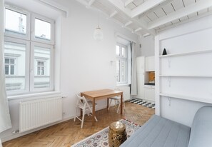 Ein Zimmer mit Holztisch, weißen Stühlen, einem gemusterten Teppich und einer Couch.