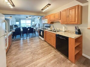A kitchen with wooden cabinets, a dishwasher, and a dining area with chairs and a table.