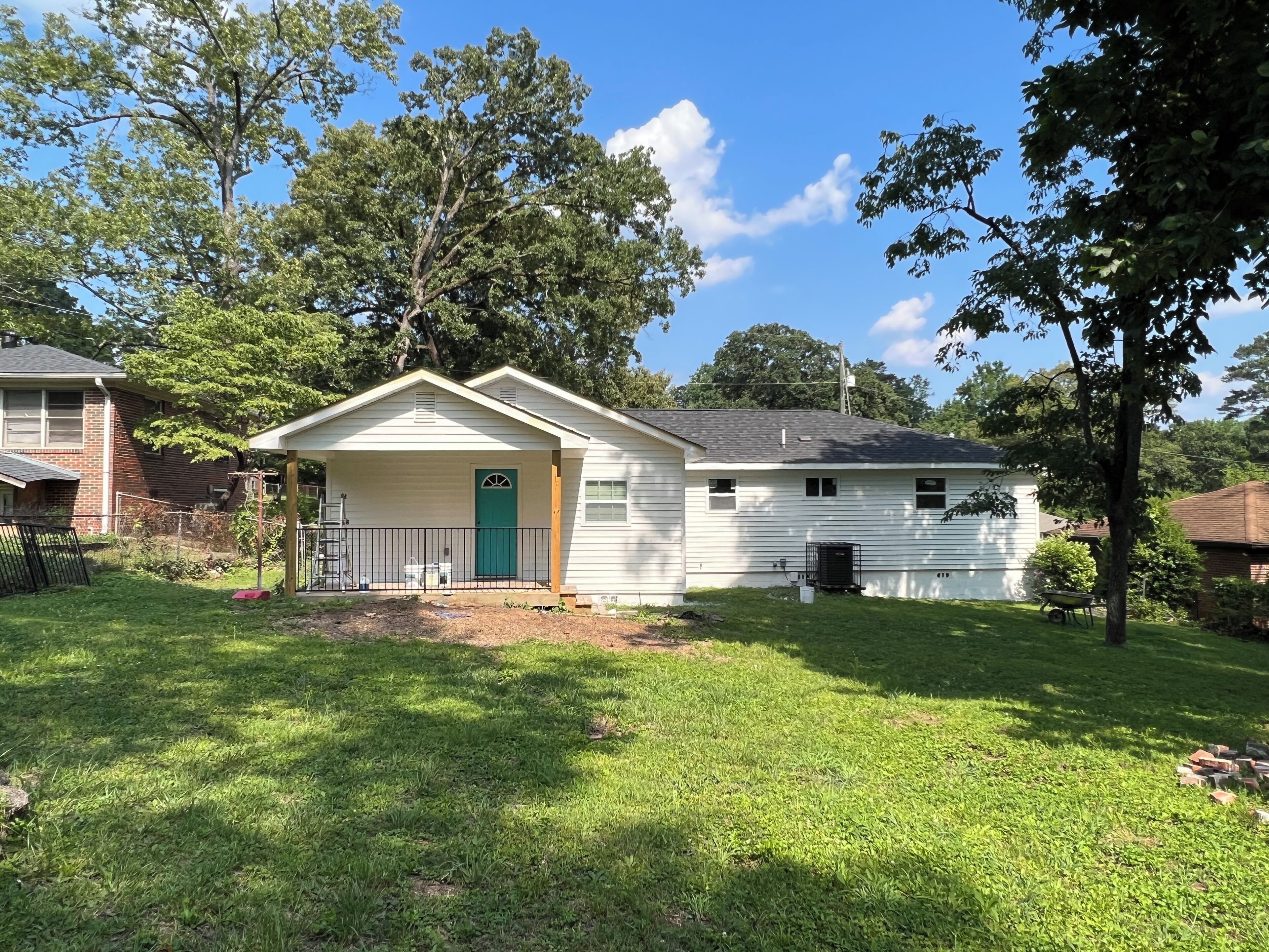 A single-story house with a front porch, a green door, and a small attached garage.