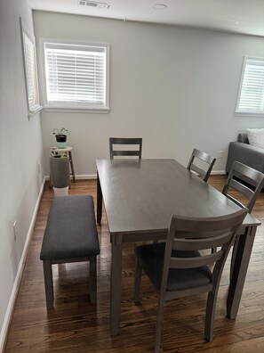 A dining area with a wooden table, four chairs, a bench, and a small stool with a plant. - Charming house in lovely Birmingham with cool AC for relaxing stays (Birmingham)