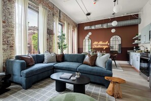 Ein modernes Wohnzimmer mit einem blauen Sofa, einem Couchtisch und einer Neonreklame.