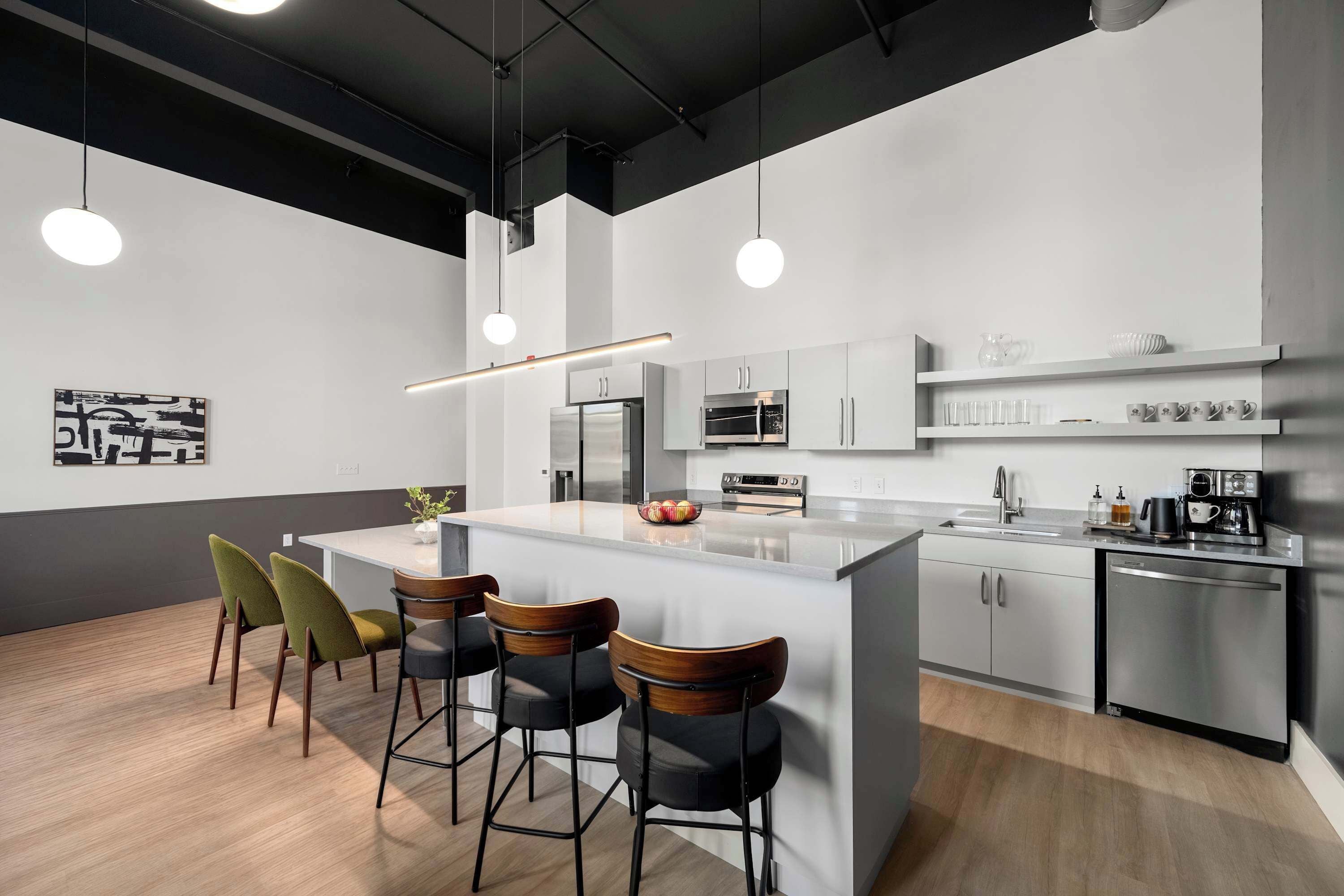 A modern kitchen with a central island, bar stools, stainless steel appliances, and pendant lighting.