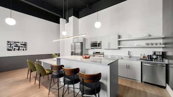 A modern kitchen with a central island, bar stools, stainless steel appliances, and pendant lighting.