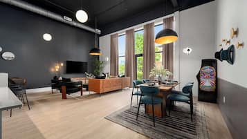 A modern living room with a sofa, dining table, chairs, and a TV.