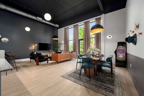 A modern living room with a sofa, dining table, chairs, and a TV. - 3 Bed w Private Patio, Mtn Views & Walk to Dining (Chattanooga)