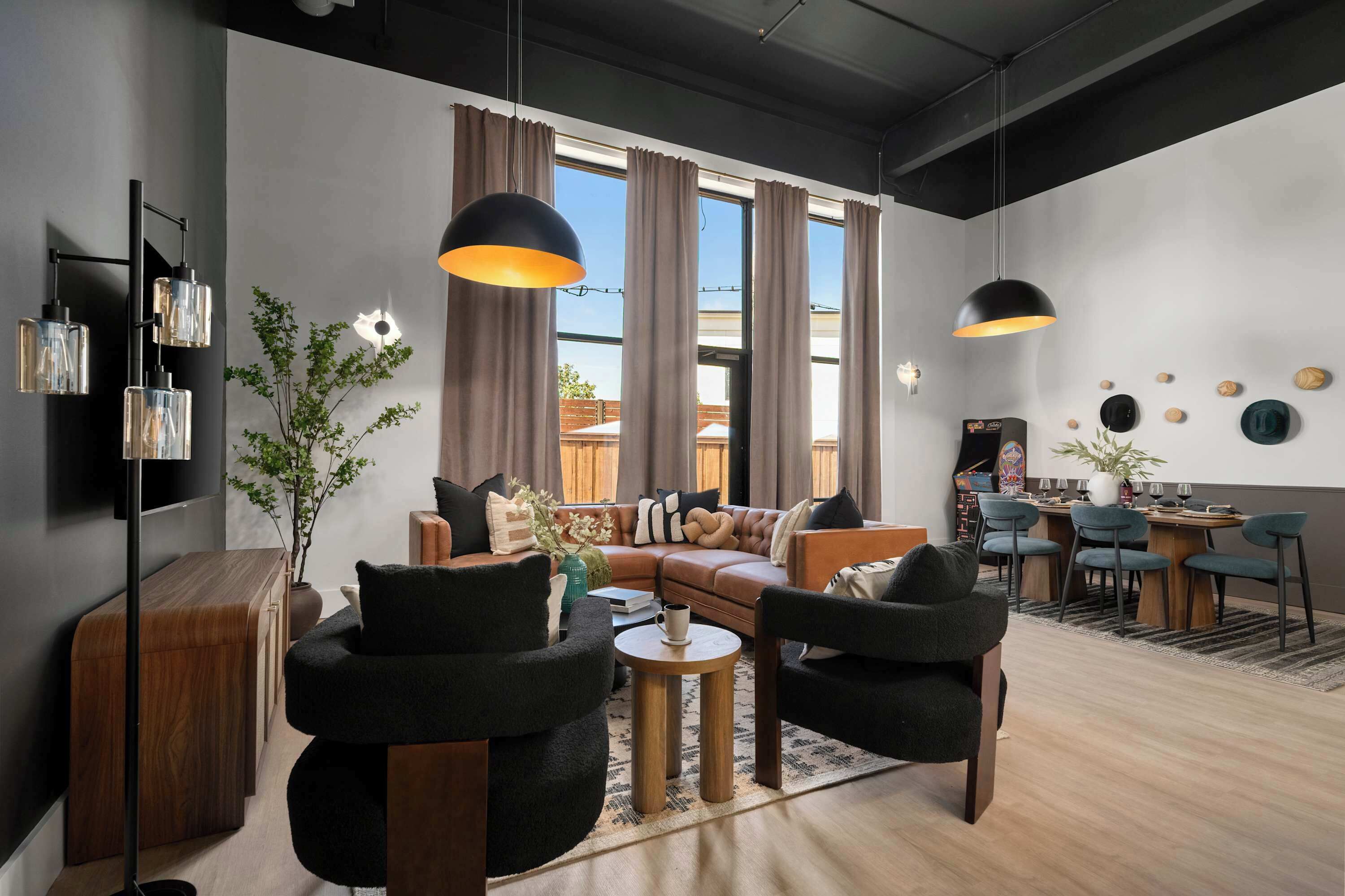 A modern living room with a sofa, chairs, a coffee table, and a dining area with chairs and a table.
