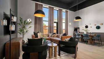 A modern living room with a sofa, chairs, a coffee table, and a dining area with chairs and a table.