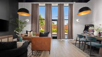 A modern living room with a sofa, chairs, a coffee table, and a dining area with chairs and a table.