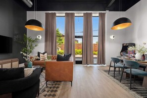 A modern living room with a sofa, chairs, a coffee table, and a dining area with chairs and a table. - 3 Bed w Private Patio, Mtn Views & Walk to Dining (Chattanooga)