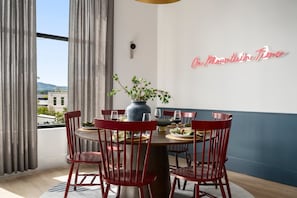A dining area with a round table, red chairs, a vase with green plants, and a neon sign on the wall. - The Ridgeline at Murals on Market (Chattanooga)