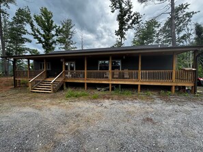 A wooden cabin with a porch, a staircase, and a gravel driveway. - Secluded Mountainside 3 Bedroom Home (Marion)