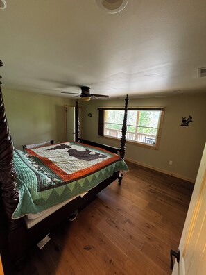 Une chambre à coucher avec un lit à baldaquin, un ventilateur de plafond, une fenêtre avec vue et un motif décoratif sur le mur.