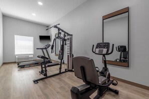 Ein Fitnessraum mit Cardiogeräten, Kraftmaschinen und einem Spiegel.