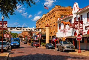 A street with a sign reading 'FORT WORTH STOCK YARDS' and a building with a horse statue. - 2 Vibrant 2-Bed Studio | Kitchenette, Free Parking | Easy Highway Access (Fort Worth)